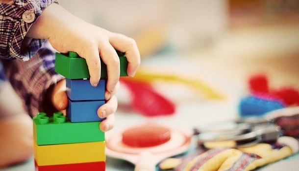Das Bild zeigt Kinderhände welche mit Bausteinen spielen.